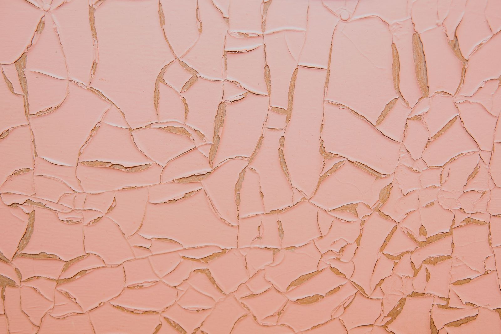 A crack running down through an old sand and cement render on a house wall