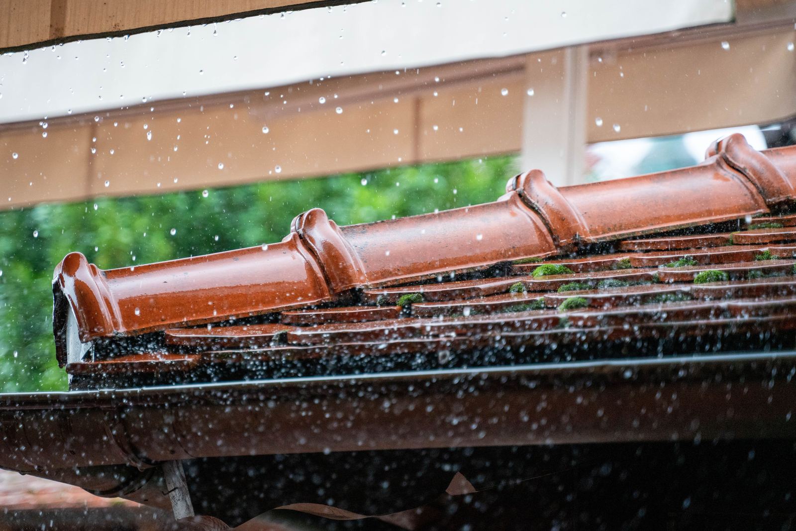 Rain falling on a tiled roof edge and the gutter below