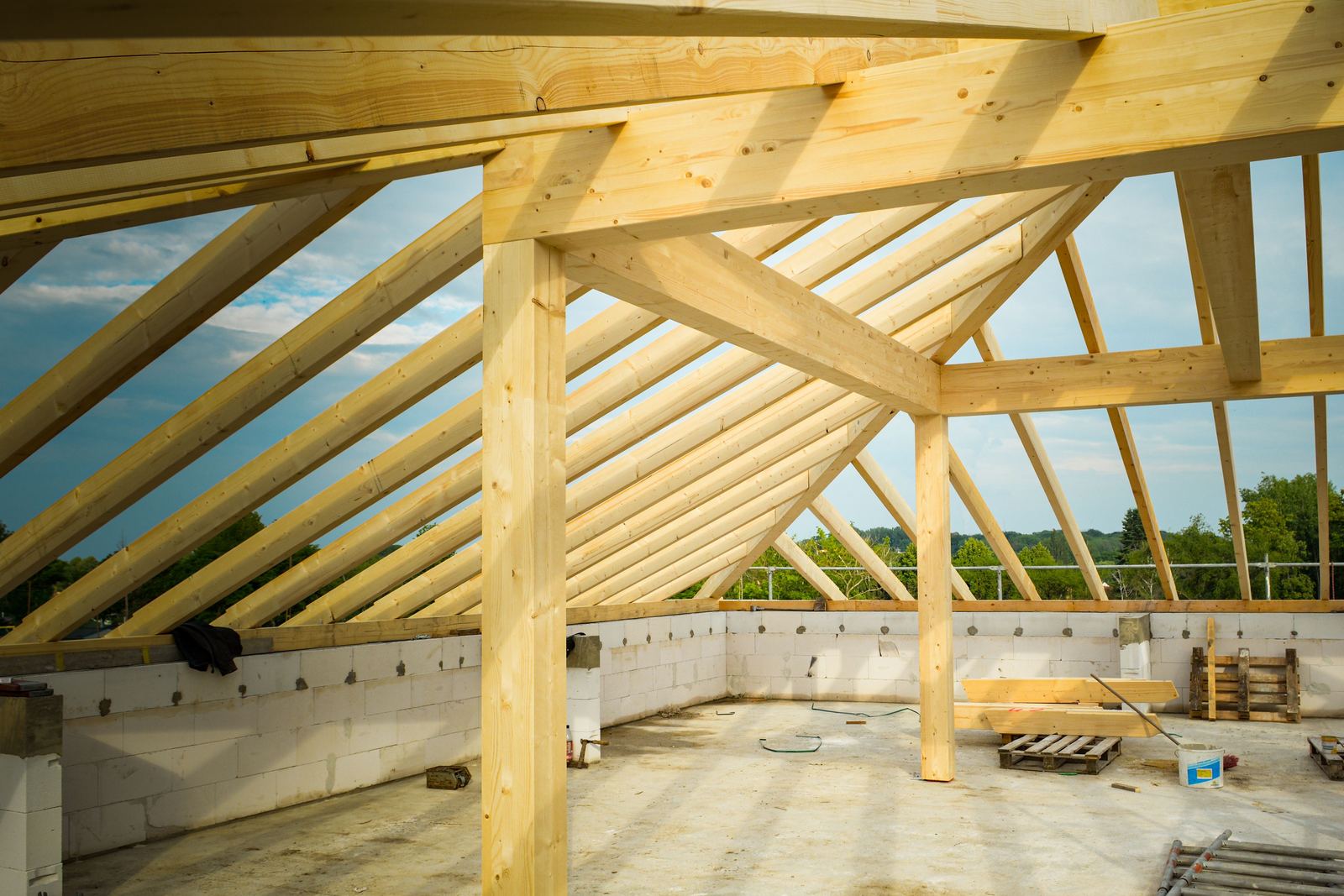 New timber roof frame of rafters and posts over unfinished block walls, open to the sky
