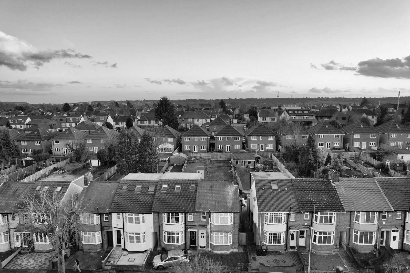 Black and white aerial view of rows of semi-detached and terraced houses with back gardens