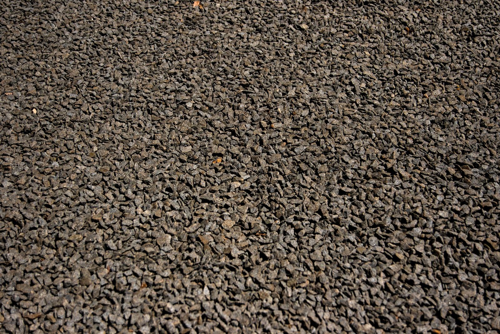 Close-up of loose dark grey gravel chippings spread evenly across the ground