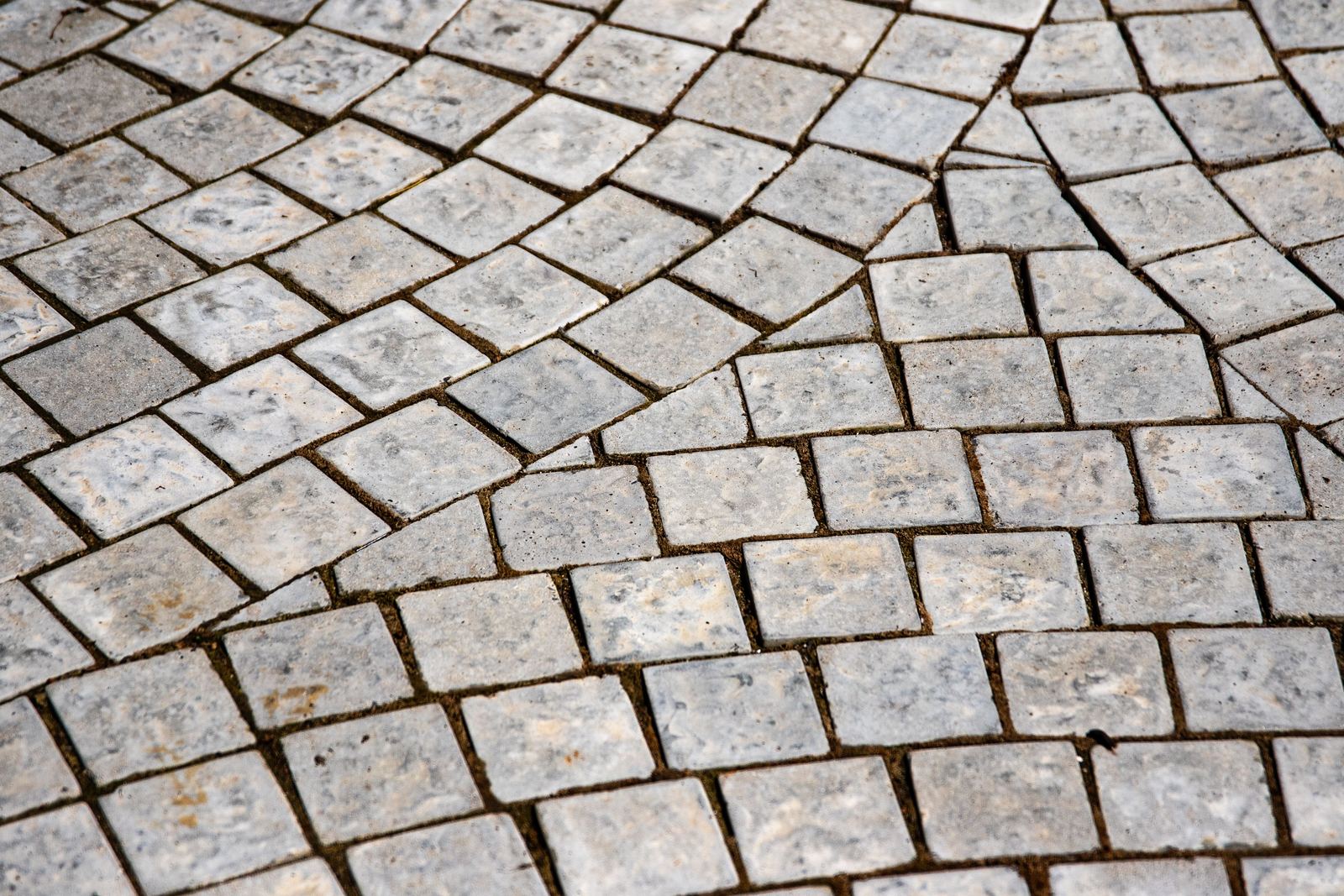 Grey square stone setts laid in curving rows across a paved surface