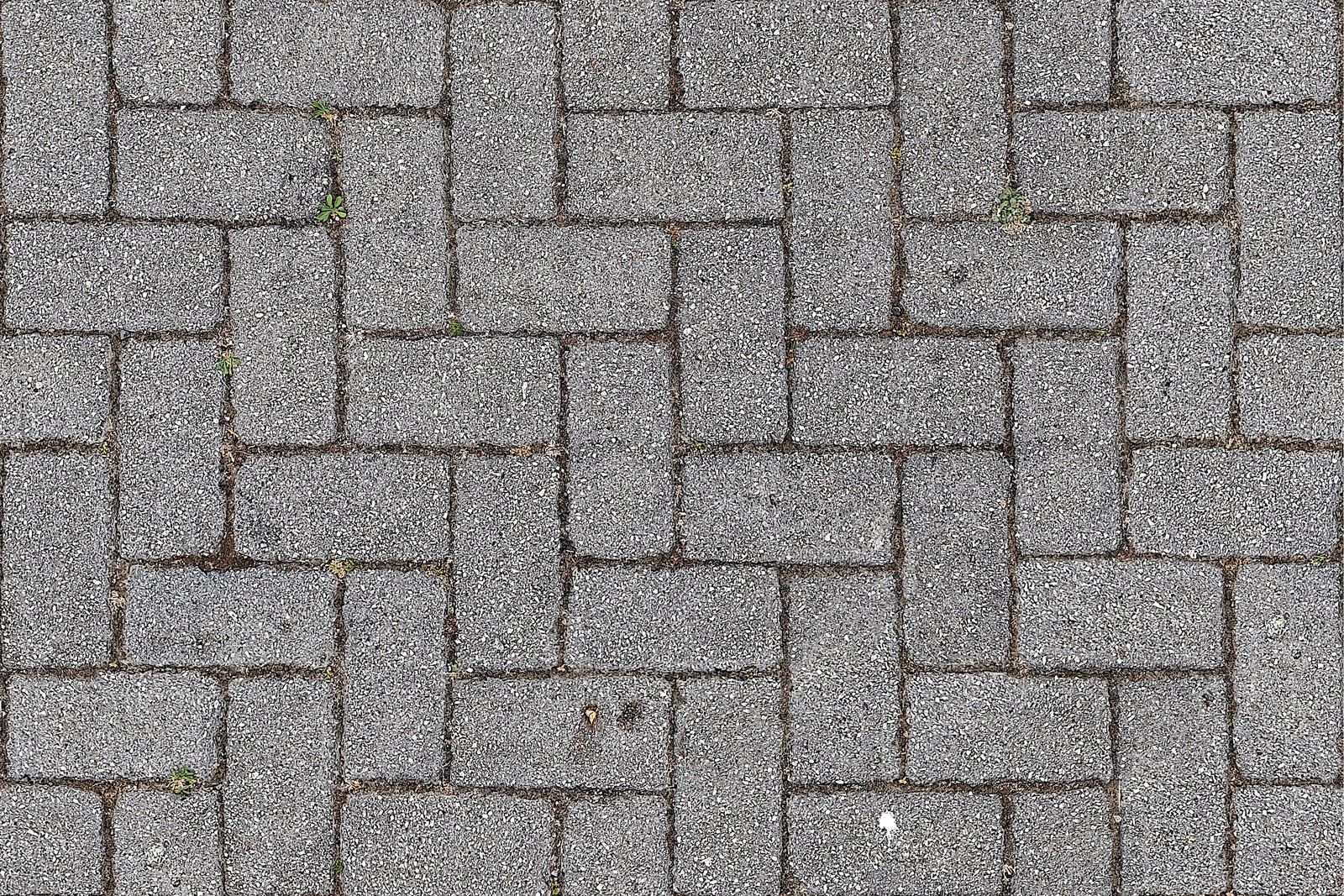 Grey concrete block paving laid in a herringbone pattern, close up