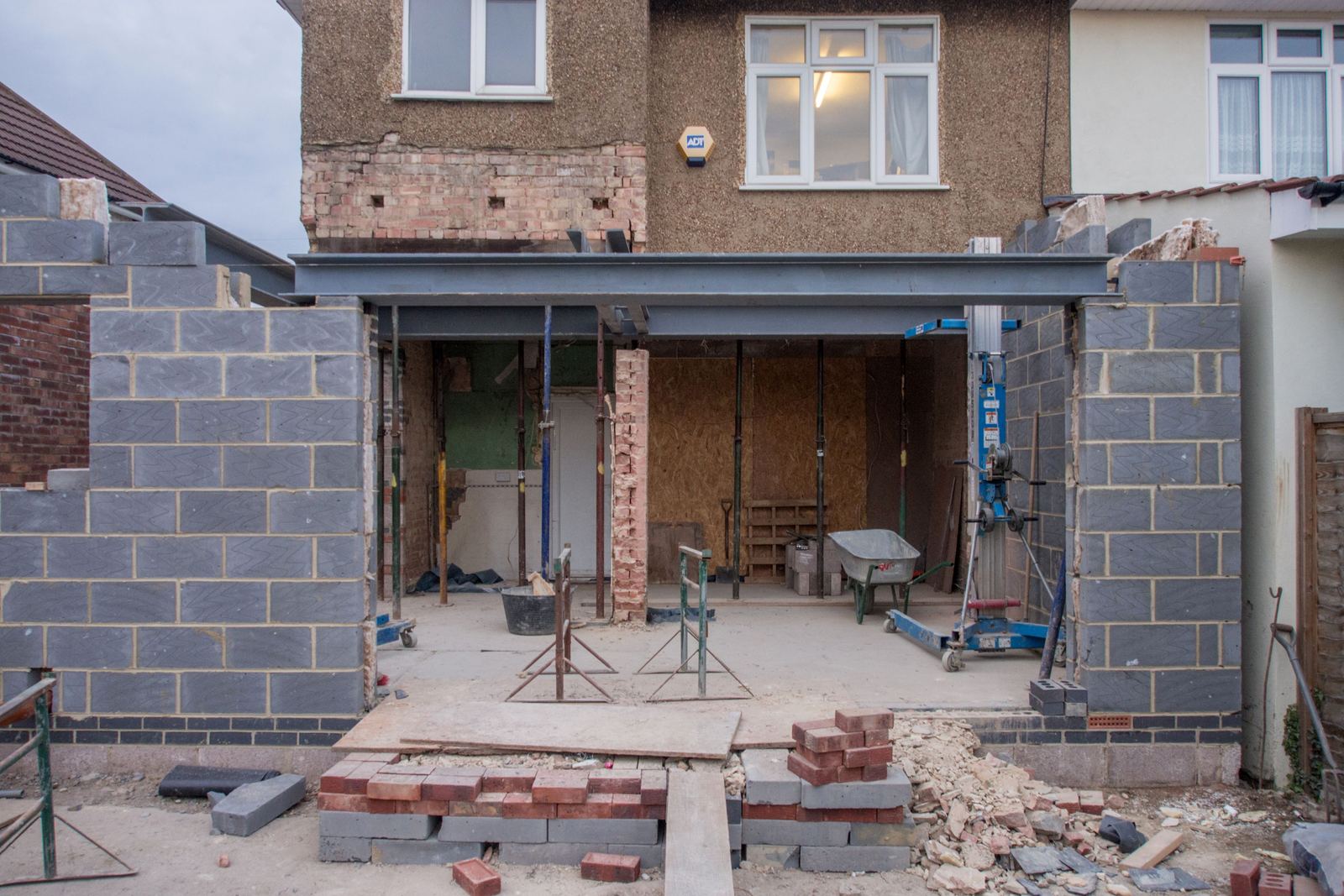 A single-storey rear extension under construction on a semi-detached house, blockwork walls going up