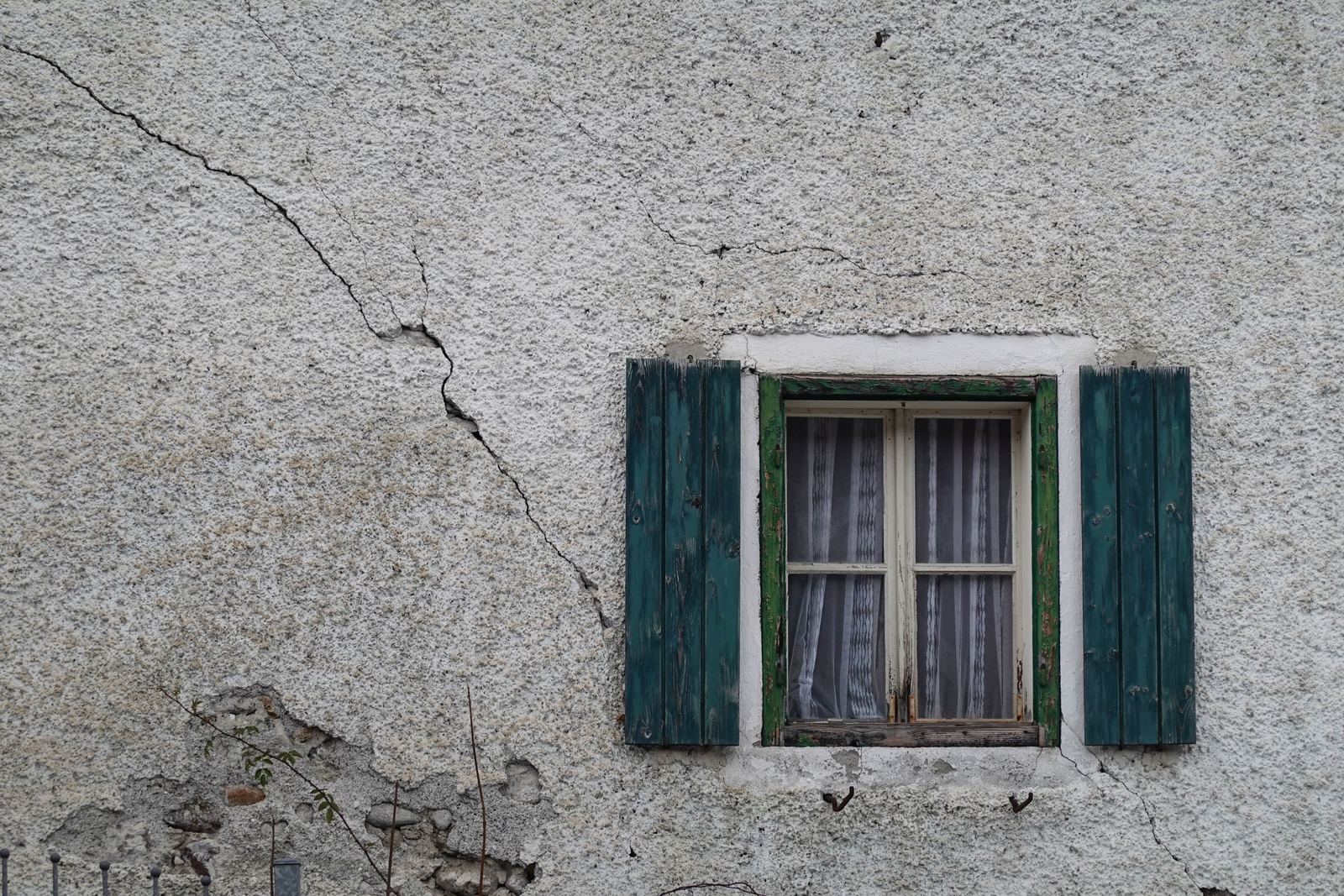 A crack running diagonally across a rendered wall from the corner of a window