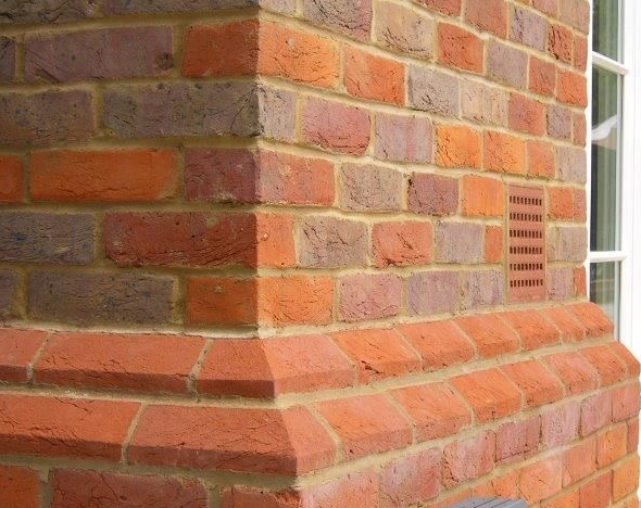 Newly built brick corner with a moulded plinth course and airbrick, laid to match existing