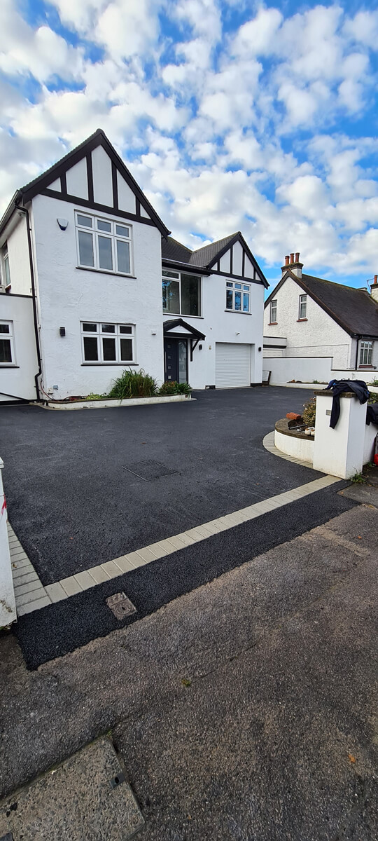 Black tarmac driveway edged with buff block paving