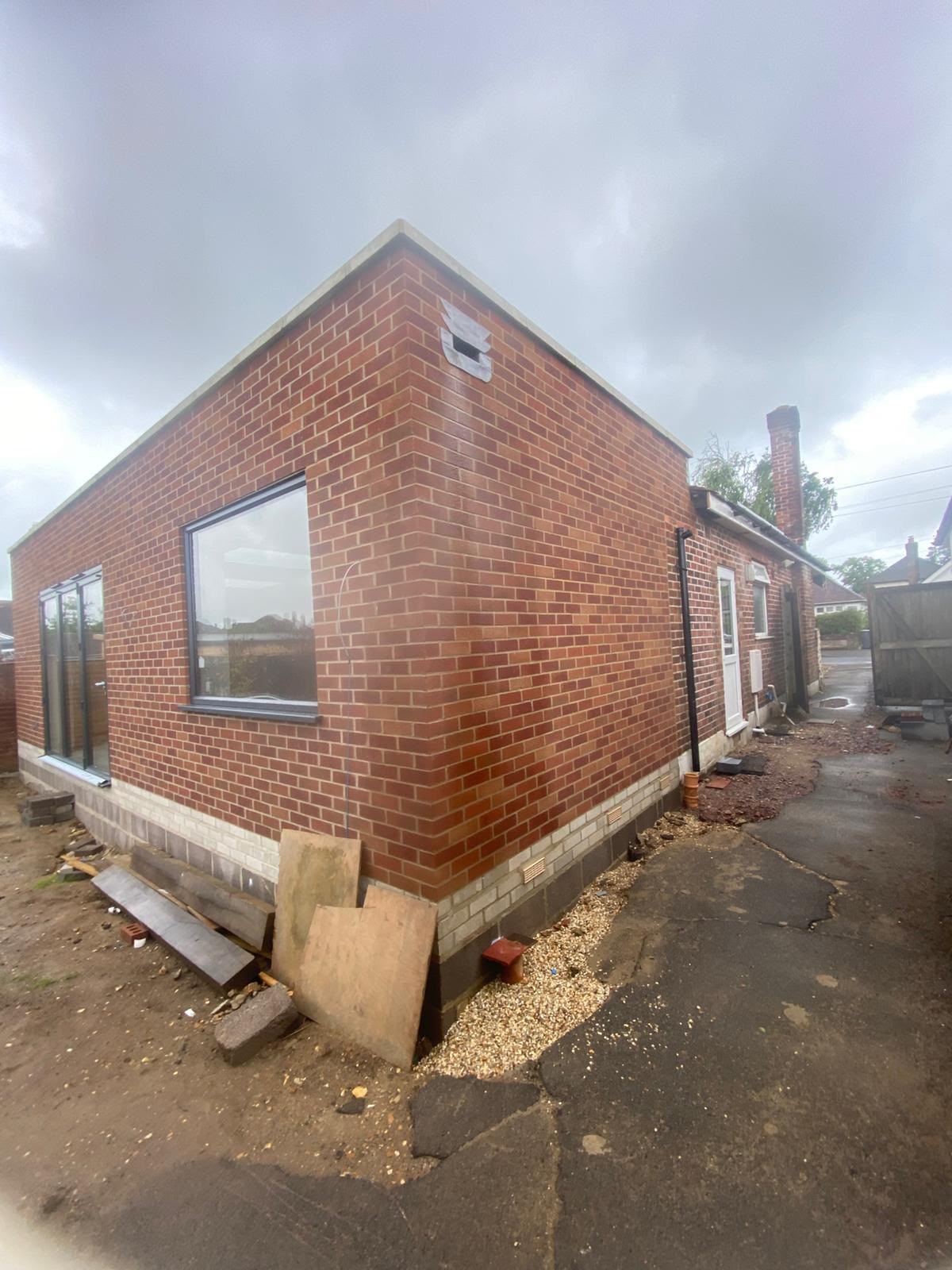 Single storey rear extension in matching red brick with the window opening formed and the roof edge on