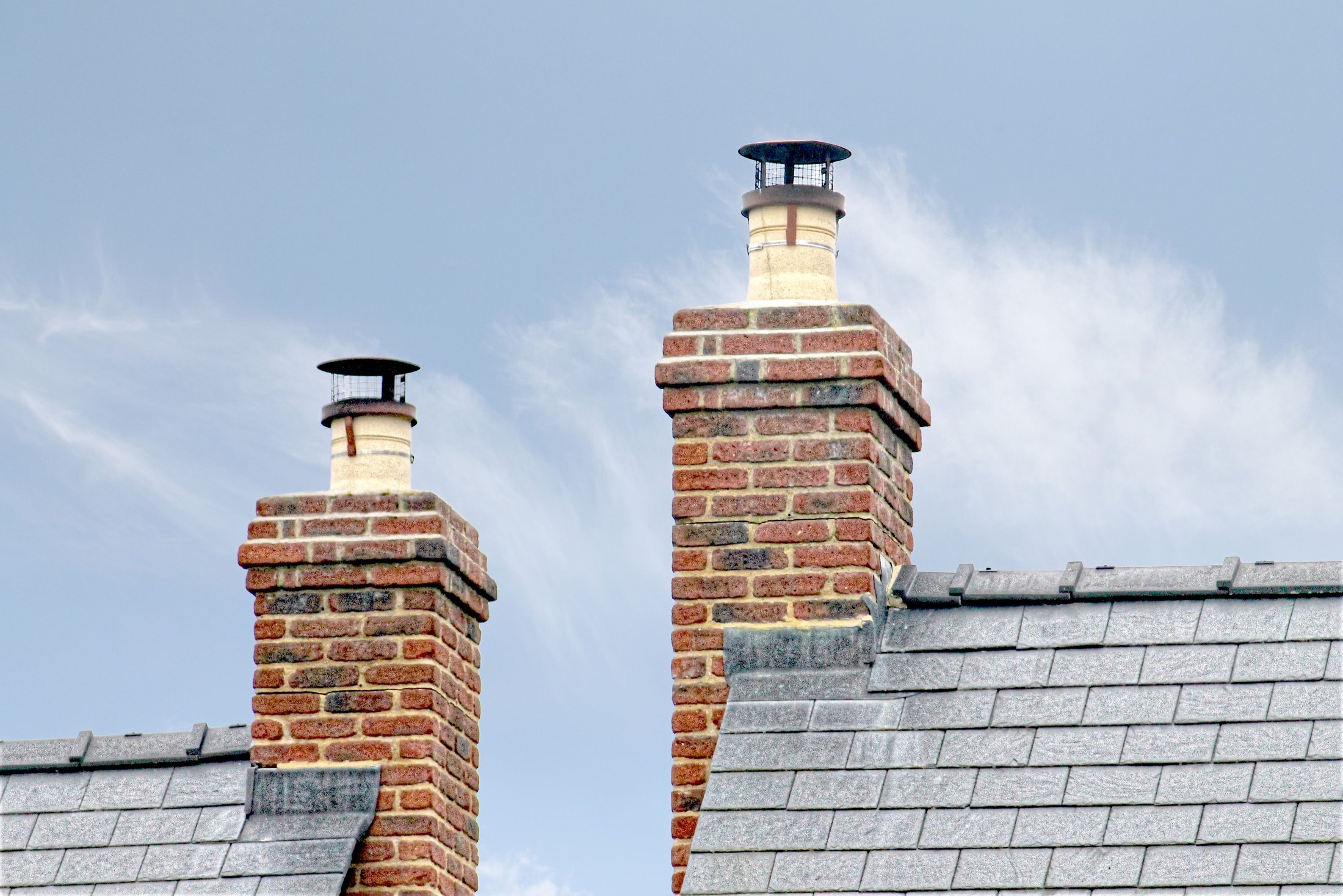Traditional brick chimneys rising through a weathered slate roof