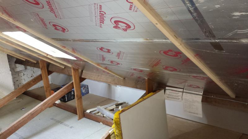 Rigid foil faced insulation boards cut and fitted between roof rafters