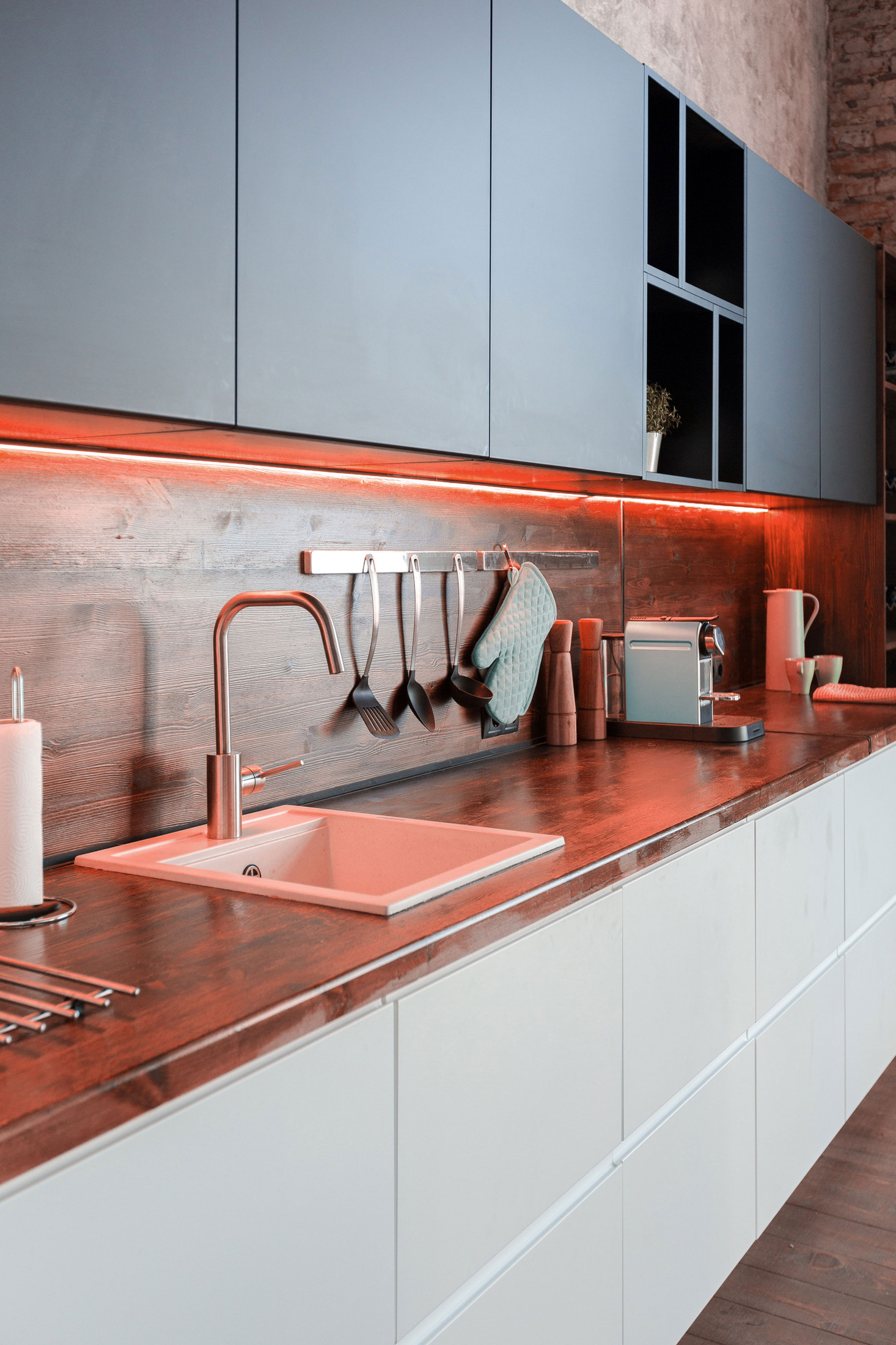 Modern fitted kitchen with handleless grey and white units, a wood-effect worktop and under-unit lighting