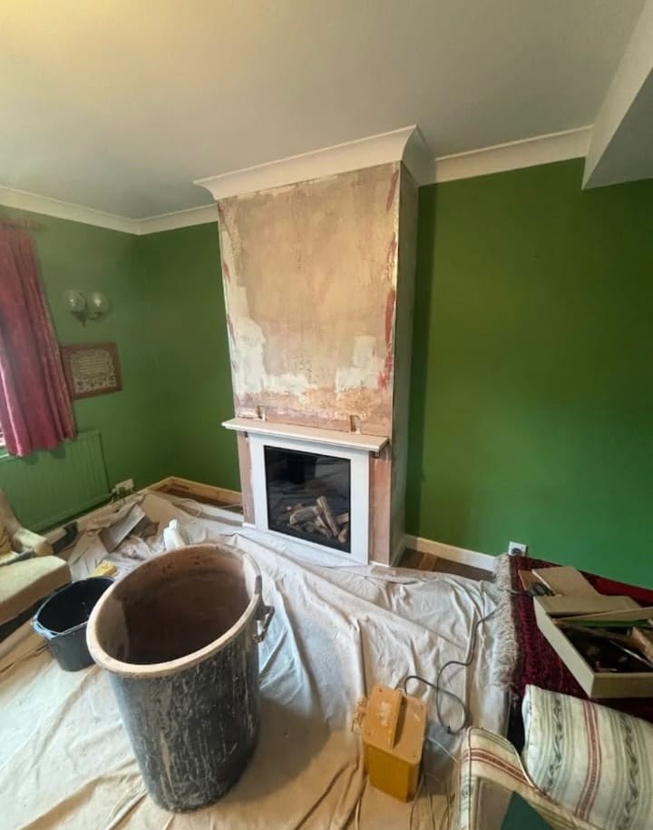 Chimney breast hacked back to bare backing before skimming, with the room sheeted up
