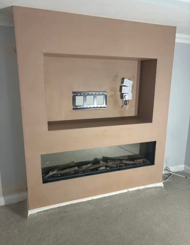 Newly plastered media wall with a recessed television alcove and a fireplace opening