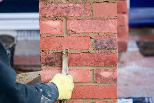 Repointing a red brick pier, raked-out joints being filled with fresh mortar