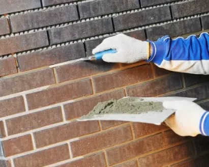 Repointing a brick wall by hand, mortar being struck into a raked-out joint