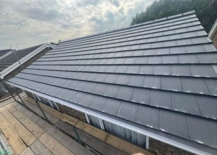 Finished flat profile tiled roof seen from the scaffold with new fascia and gutter running true